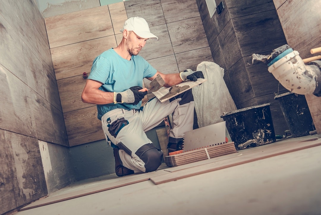 Architect putting glue on bathroom tiles