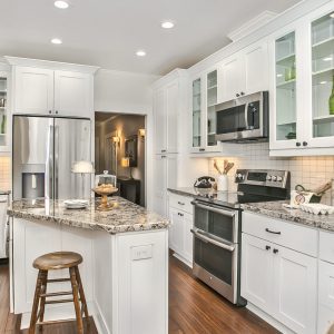 Kitchen with granite countertop and white cabinetry and appliances