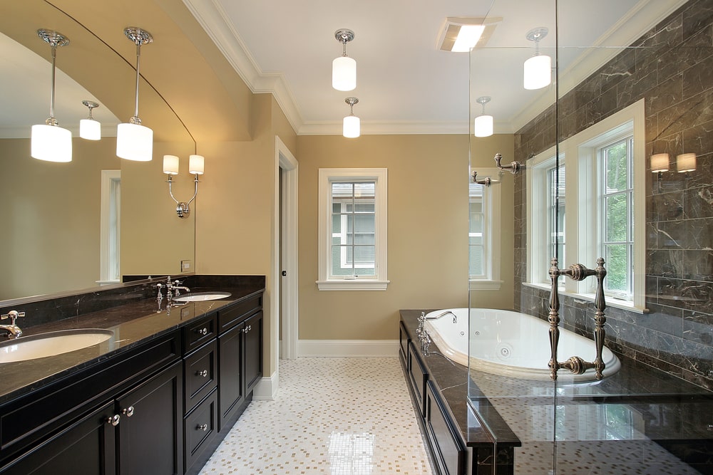 Bathroom with black cabinetry and white tub and ambient lighting