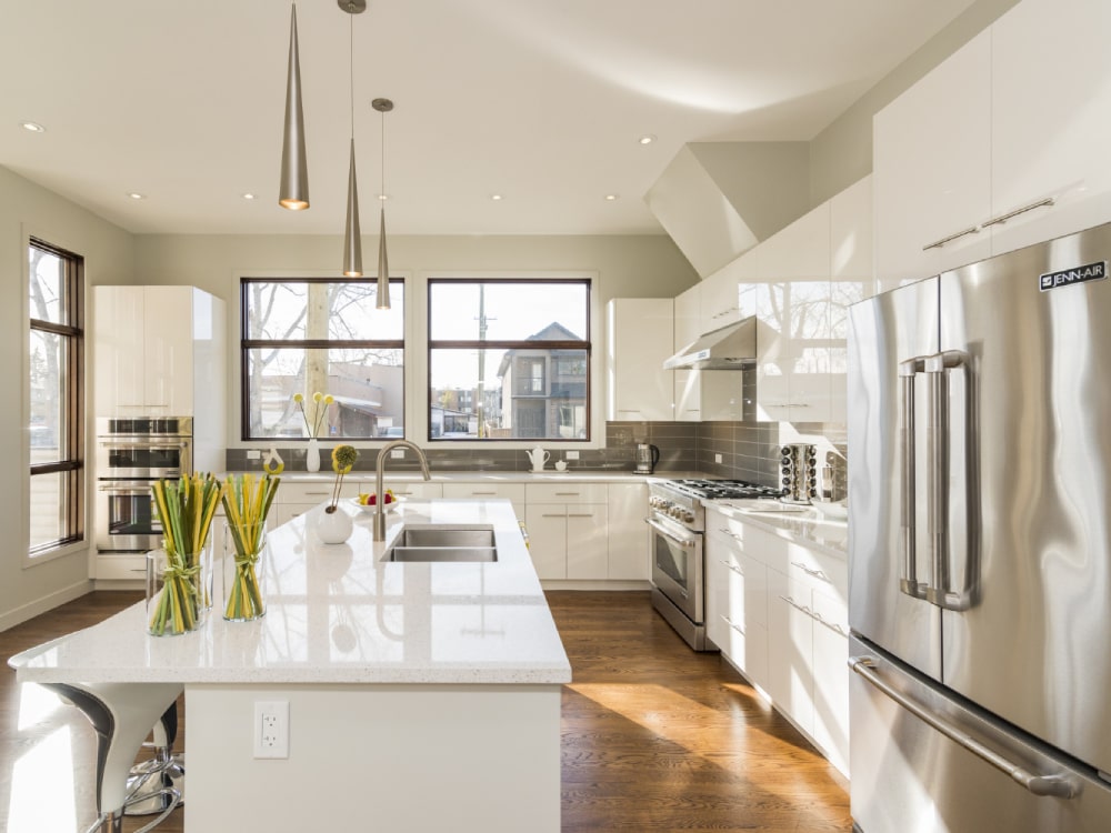 White countertop & cabinetry at kitchen with dining room behind and lots of windows around