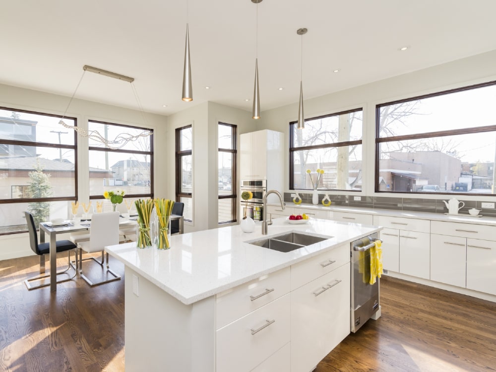 White countertop at kitchen with dining room behind and lots of windows around