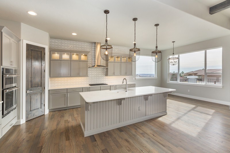 a kitchen that has white cabinets and wood flooring