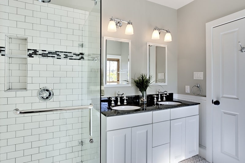 Bathroom with marble tiles, two sinks and lamps with shower at the side