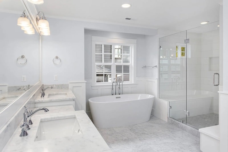 Bathroom with two sinks, bathtub, and shower in new luxury home