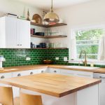 A beautifully designed kitchen featuring a green tile backsplash.