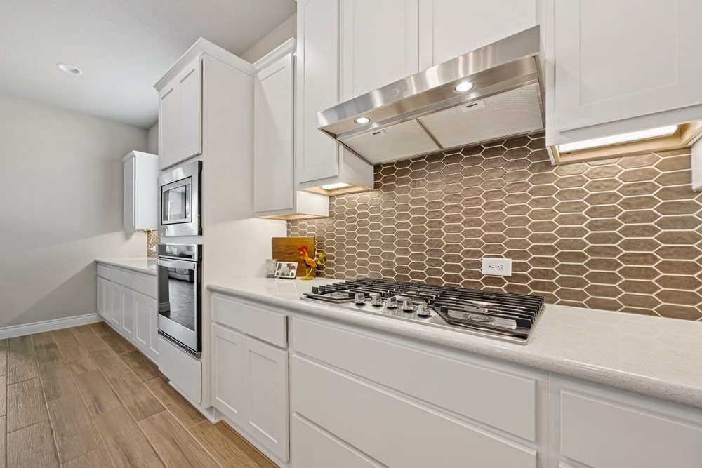 A beautifully designed kitchen featuring a green tile backsplash.