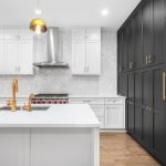 A modern kitchen with white cabinets and black hardware detailing.