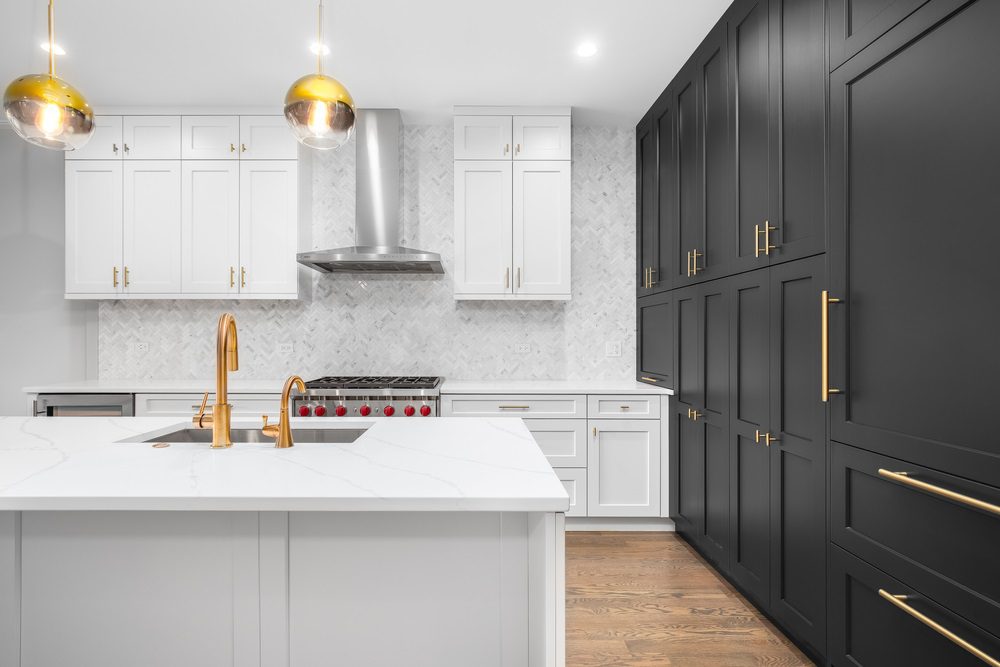 A modern kitchen with white cabinets and black hardware detailing.