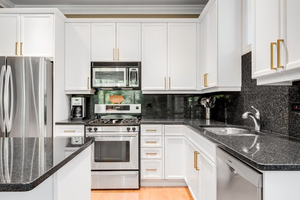 A modern kitchen with white cabinets and black hardware detailing.