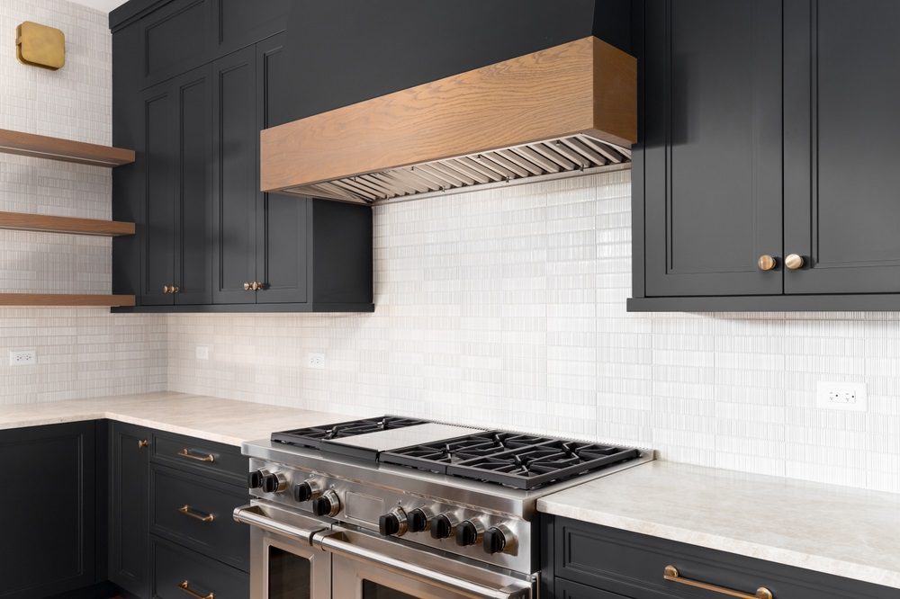 A modern kitchen with white cabinets and black hardware detailing.