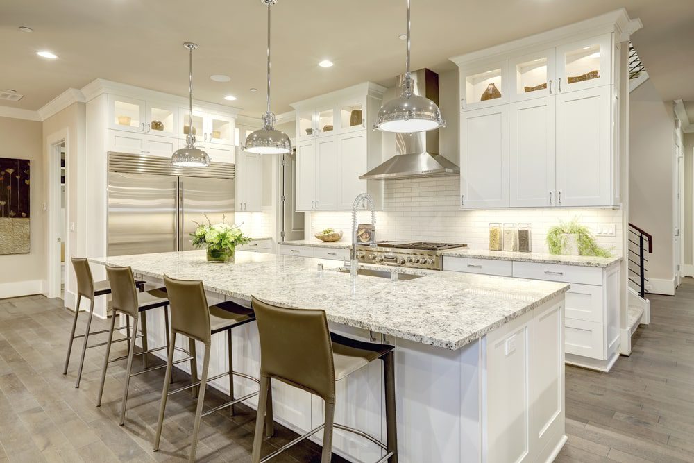 A modern kitchen remodel with sleek cabinets, a marble countertop, and stainless steel appliances.