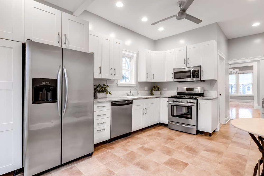 A modern kitchen remodel with sleek cabinets, a marble countertop, and stainless steel appliances.