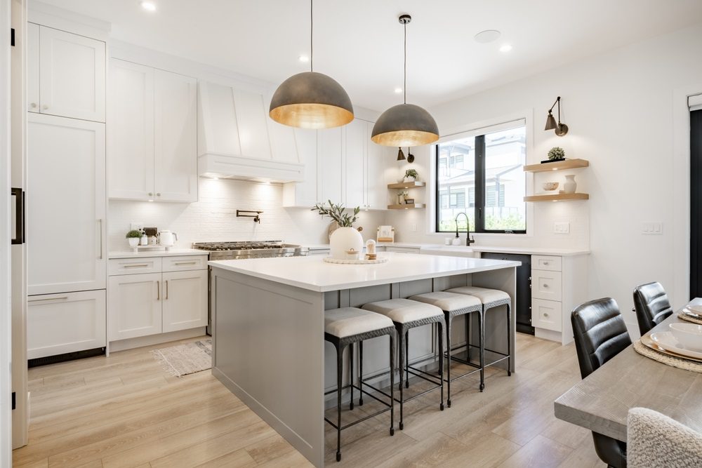 Kitchen island decorated with pendant lighting, greenery, and a fruit bowl.