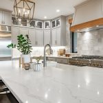 Kitchen island decorated with pendant lighting, greenery, and a fruit bowl.