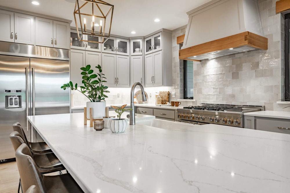 Kitchen island decorated with pendant lighting, greenery, and a fruit bowl.