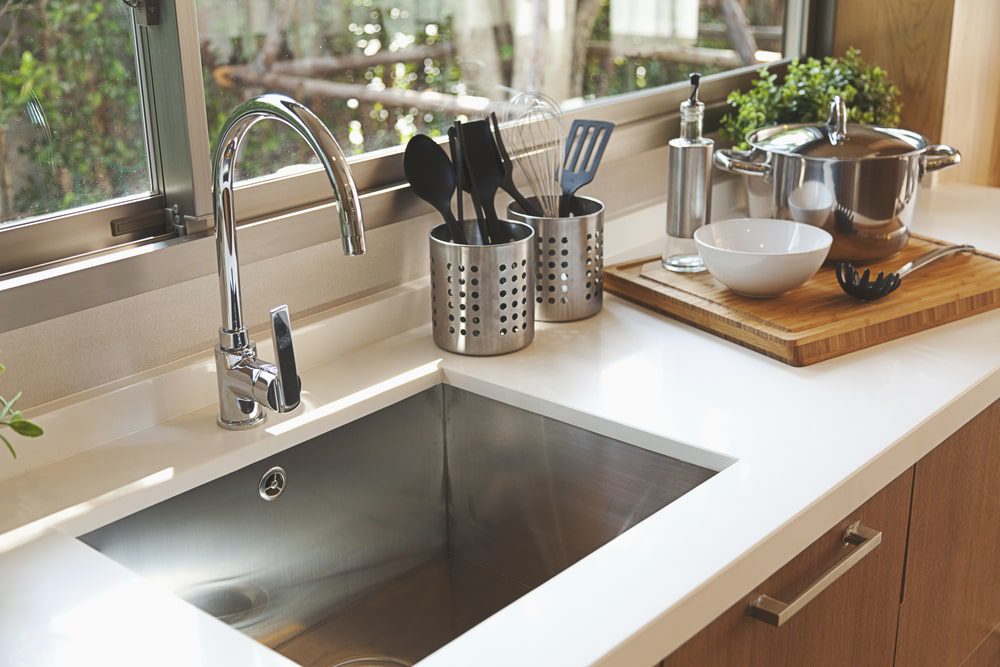  Plumber installing a modern kitchen sink faucet in a newly remodeled kitchen
