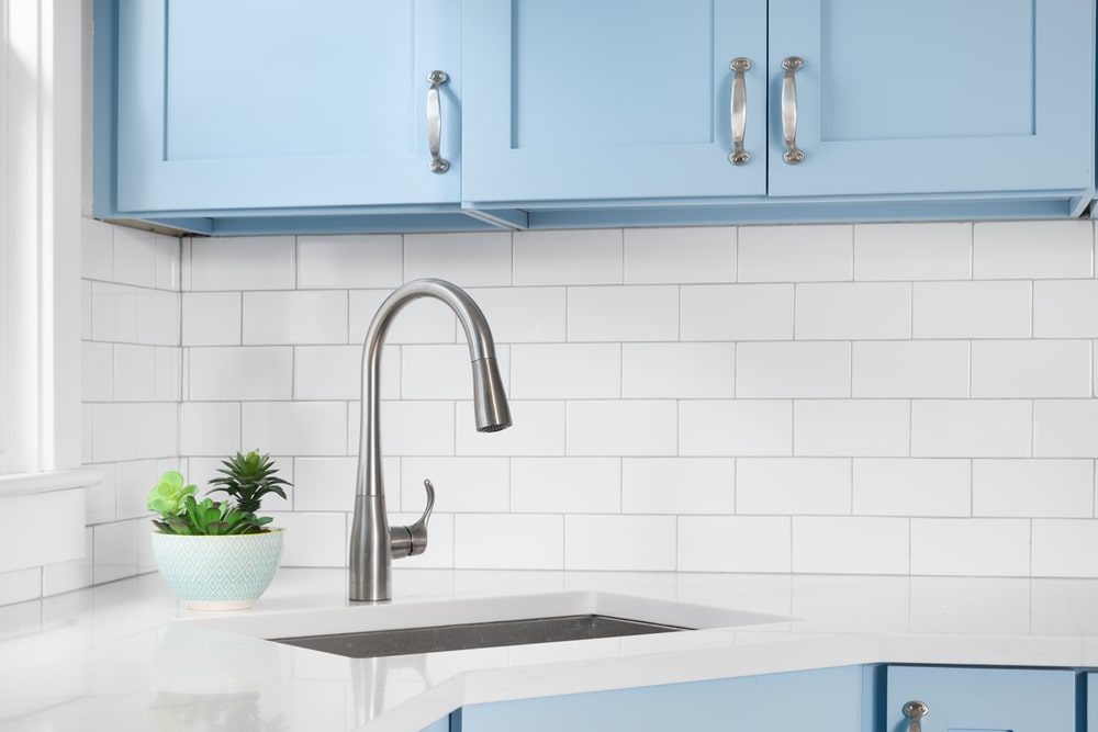  Plumber installing a modern kitchen sink faucet in a newly remodeled kitchen
