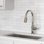 Plumber installing a modern kitchen sink faucet in a newly remodeled kitchen