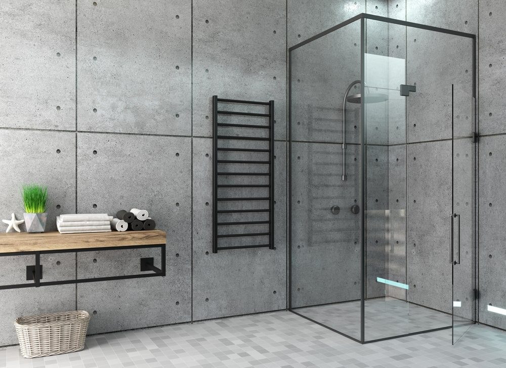 Installer aligning a frameless glass shower door with a level and suction cups over tiled walls