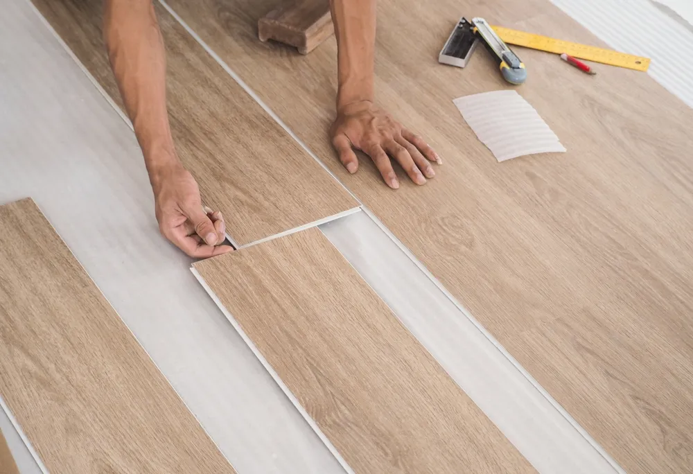 DIY bathroom with vinyl tile flooring being installed, tiles aligned along a chalk reference line