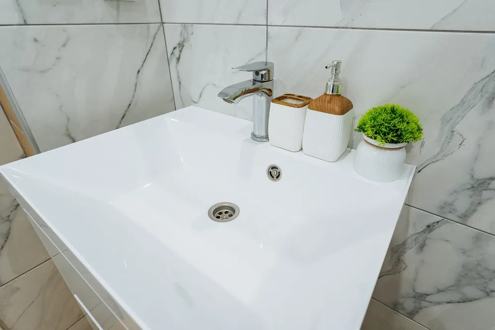 Person tightening a bathroom sink faucet during installation