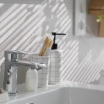 Person tightening a bathroom sink faucet during installation