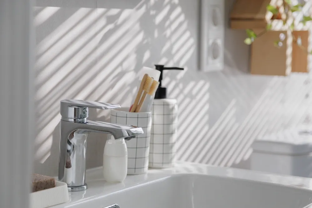 Person tightening a bathroom sink faucet during installation