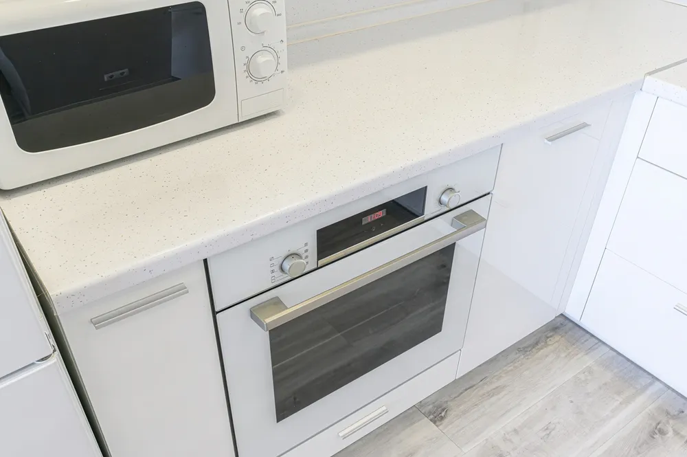 Laminate kitchen countertop being refinished with countertop paint, roller, primer, and protective top coat