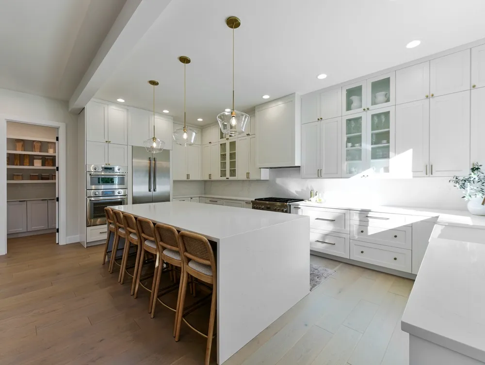 Homeowner measuring kitchen cabinets with a tape measure while recording cabinet dimensions on a floor plan
