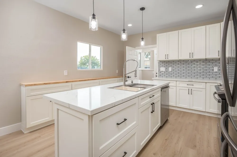 Homeowner measuring kitchen cabinets with a tape measure while recording cabinet dimensions on a floor plan