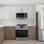 Kitchen with coordinated cabinets, tile flooring, quartz countertops, and warm modern lighting