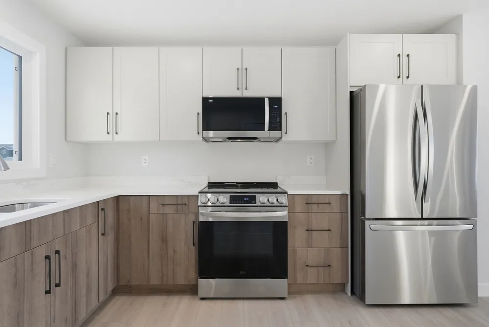 Kitchen with coordinated cabinets, tile flooring, quartz countertops, and warm modern lighting