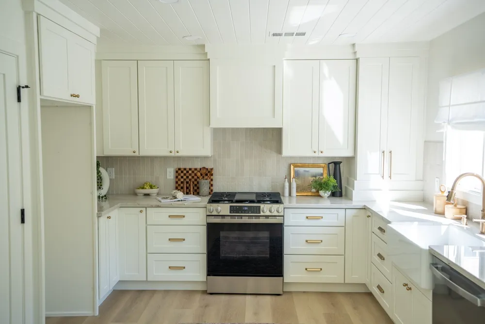 Kitchen with coordinated cabinets, tile flooring, quartz countertops, and warm modern lighting
